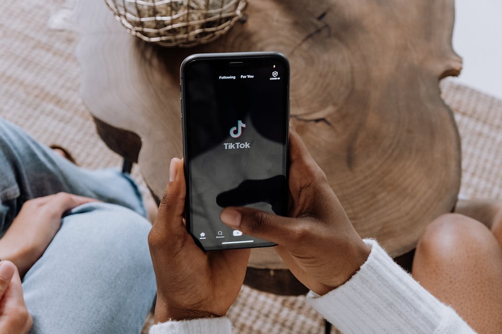 Person sitting holding phone with TikTok on screen