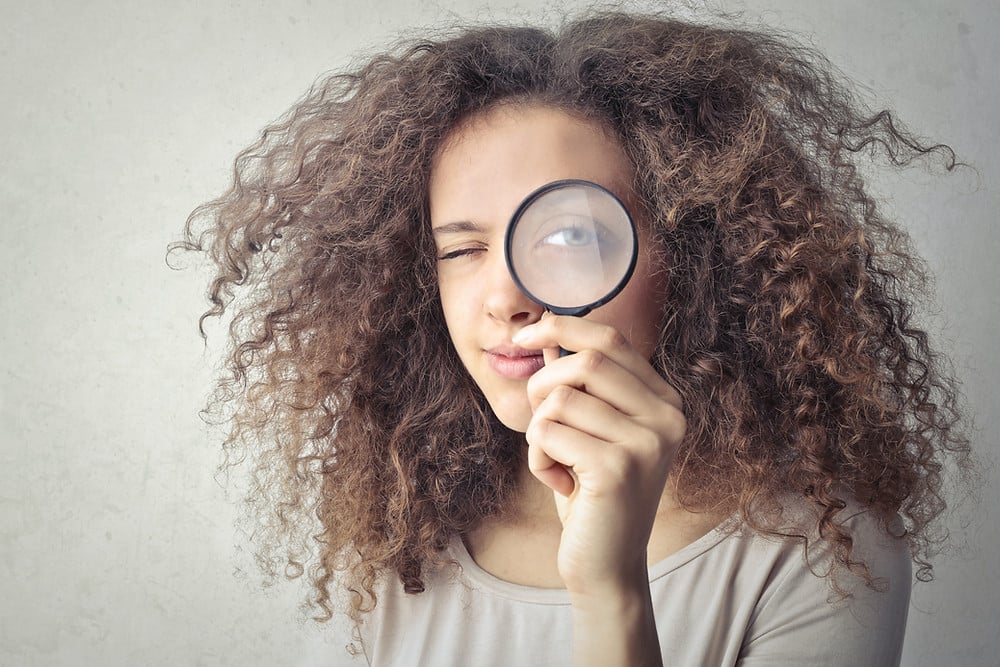 Woman looking through a magnifying glass contemplating where to meet single men